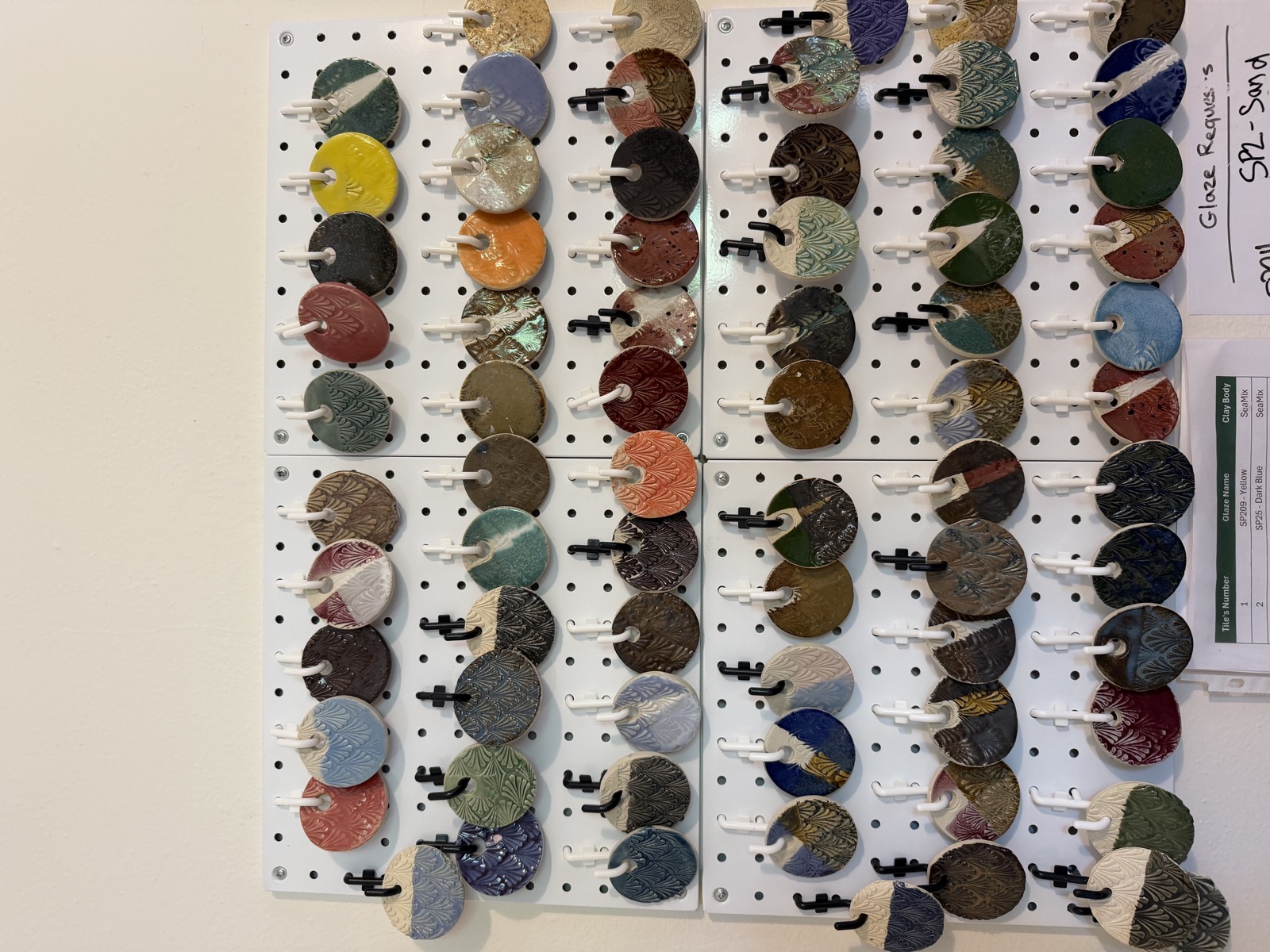 Wall of glaze color test tiles at Clay Element, organized by tile number and glaze name
