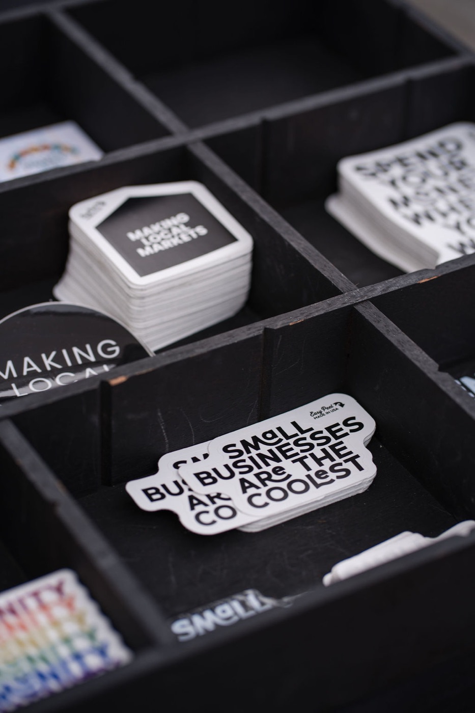 Making Local stickers in a black divided tray, one of them reading Small Businesses Are The Coolest