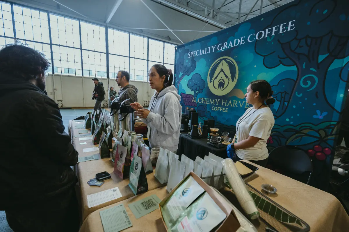 Staff at the Alchemy Harvest Coffee table talking with guests in the hangar