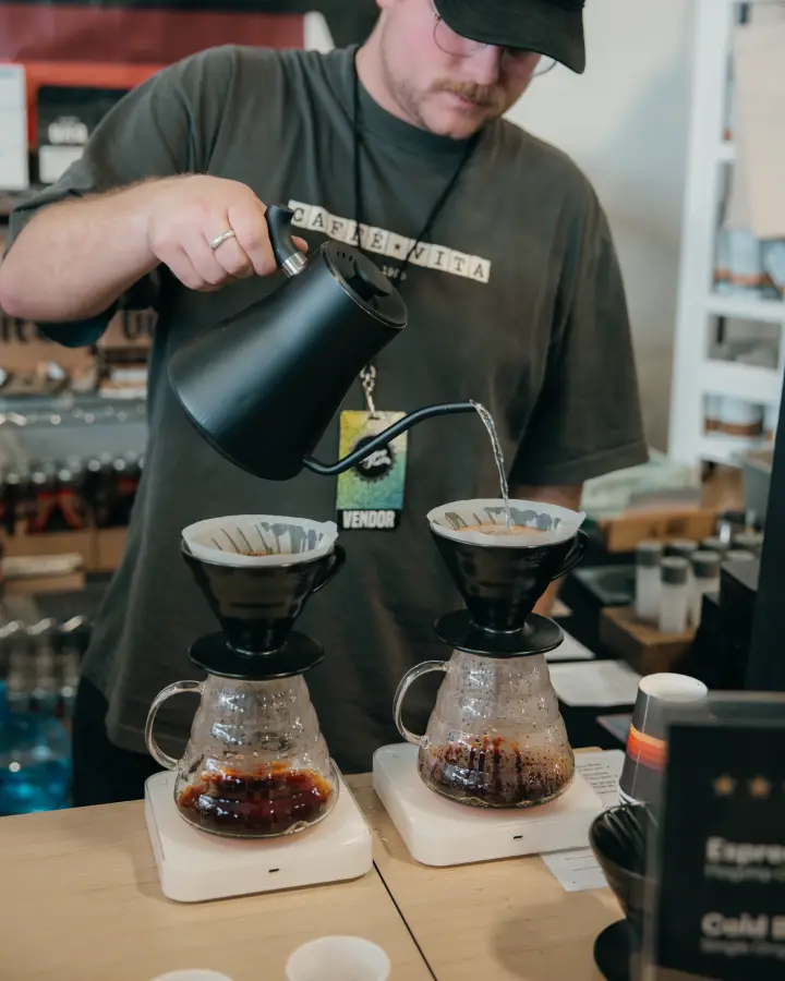 A vendor pouring water over two pour-over drippers