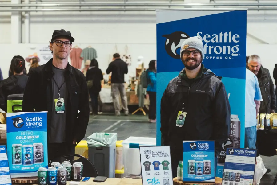 Two vendors smiling at the Seattle Strong Coffee Co. booth